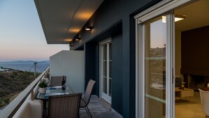 A balcony with a table and chairs, a bottle of wine, and a view of the sea. - CHROMA Lodge Rafina (Rafina-Pikermi)