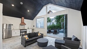A modern kitchen with a stainless steel refrigerator, a built-in oven, and a large window overlooking a patio. - THE PEARL!  7bd/7ba IOP Home Private POOL & Ocean VIEWS! (Isle Of Palms)