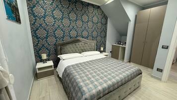 A bedroom with a large bed, a nightstand, a dresser, and a wardrobe.