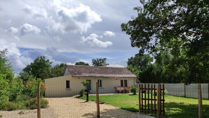 A house with a gravel driveway, a wooden gate, and a fenced yard. - A L'arborée de Clénord (Clénord-Cellettes)