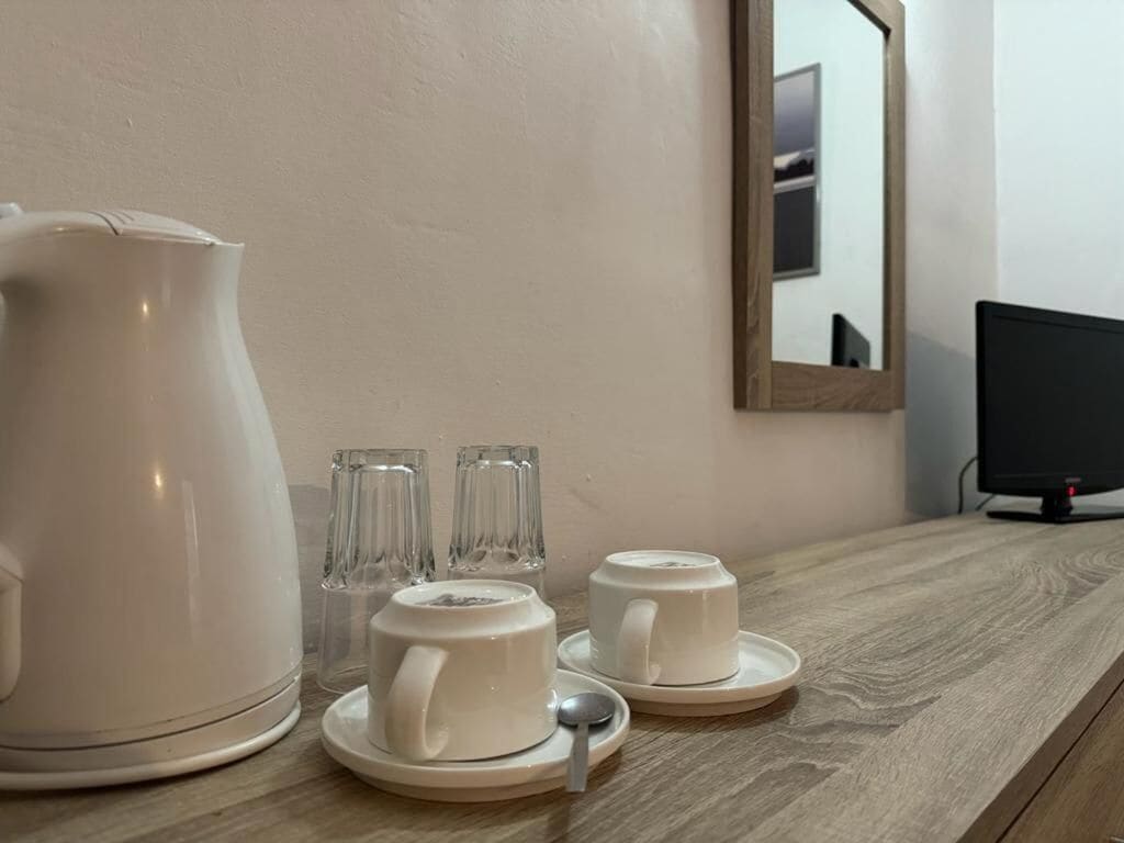 A kitchen counter with a coffee maker, two cups, and three glasses.