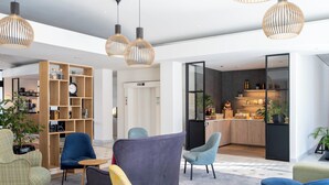 Una hall moderna con posti a sedere, una libreria in legno e un angolo cottura.