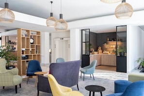 Um lobby moderno com assentos, uma estante de madeira e uma área de cozinha.