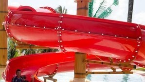 Un tobogán de agua con estructura de madera y una piscina.