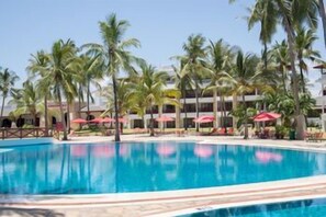 A swimming pool with palm trees and umbrellas, surrounded by a hotel building. - Prideinn Paradise Beach Resort & Spa Mombasa (Mombasa)