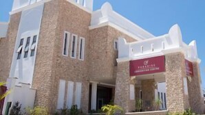 Un edificio moderno con fachada de piedra, una entrada destacada y un cartel que indica un hotel.