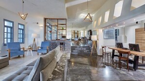 Un grand espace de vie comprenant un canapé, des fauteuils, une table à manger et une cuisine à l’arrière-plan.