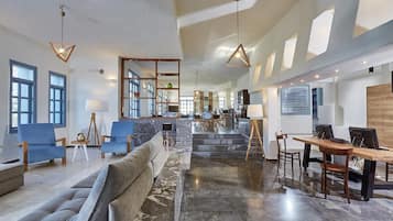 A spacious living area with a sofa, chairs, a dining table, and a kitchen in the background.