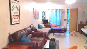 Un salon chaleureux avec un canapé en cuir marron, une petite table et un tapis coloré.
