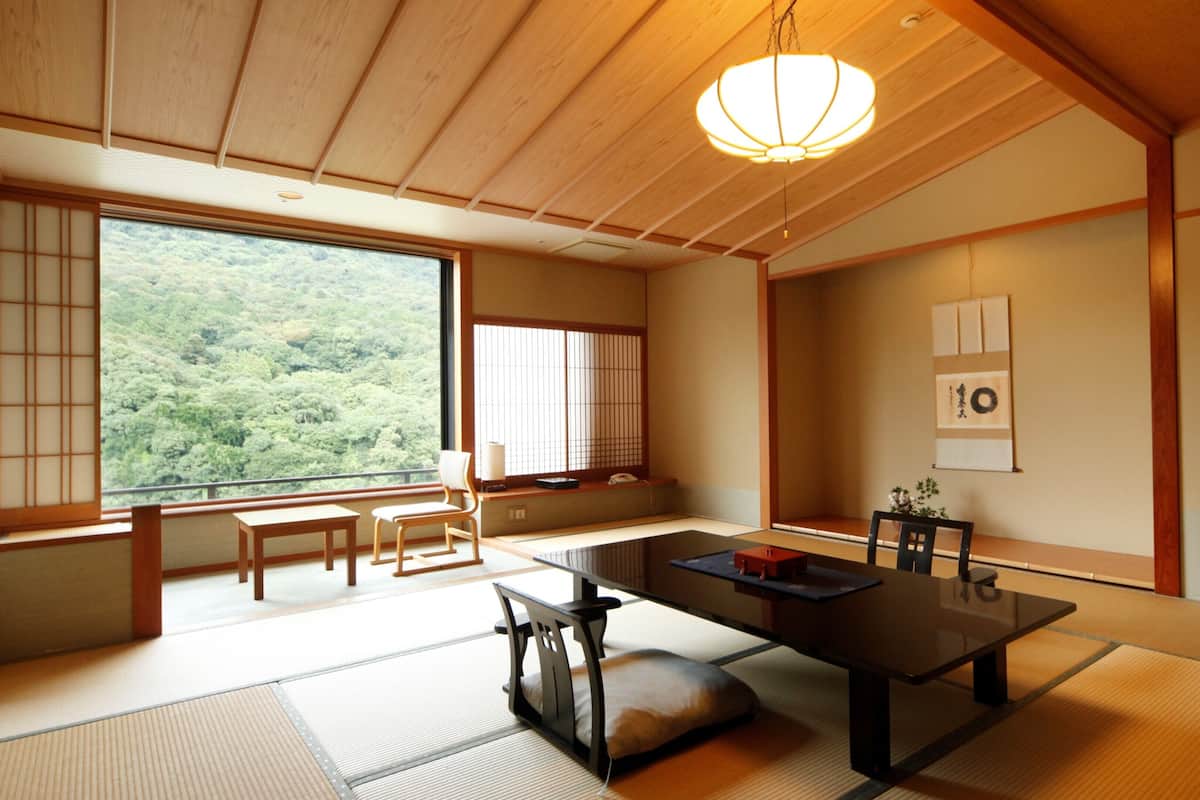 Una habitación japonesa tradicional con suelo de tatami, una mesa baja y puertas correderas.