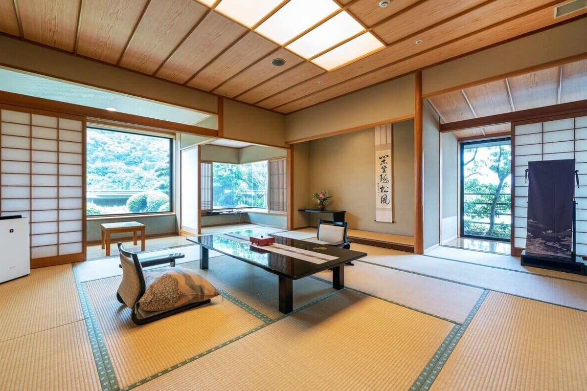 Una habitación japonesa tradicional con suelo de tatami, puertas correderas y una mesa baja con cojines.