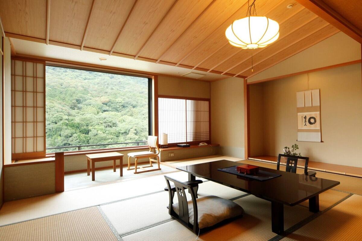 Una habitación japonesa tradicional con suelo de tatami, una mesa baja y puertas correderas.