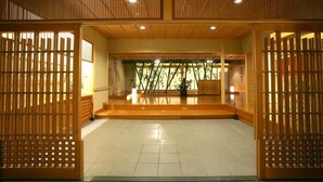 Perinteinen japanilainen sisustus, jossa on liukuovet, laattalattia ja näkymä ulos ovien läpi.