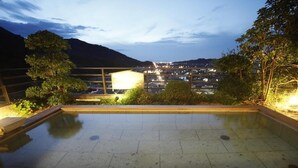 Una piscina en la azotea con vistas a un paisaje urbano y montañas al fondo.