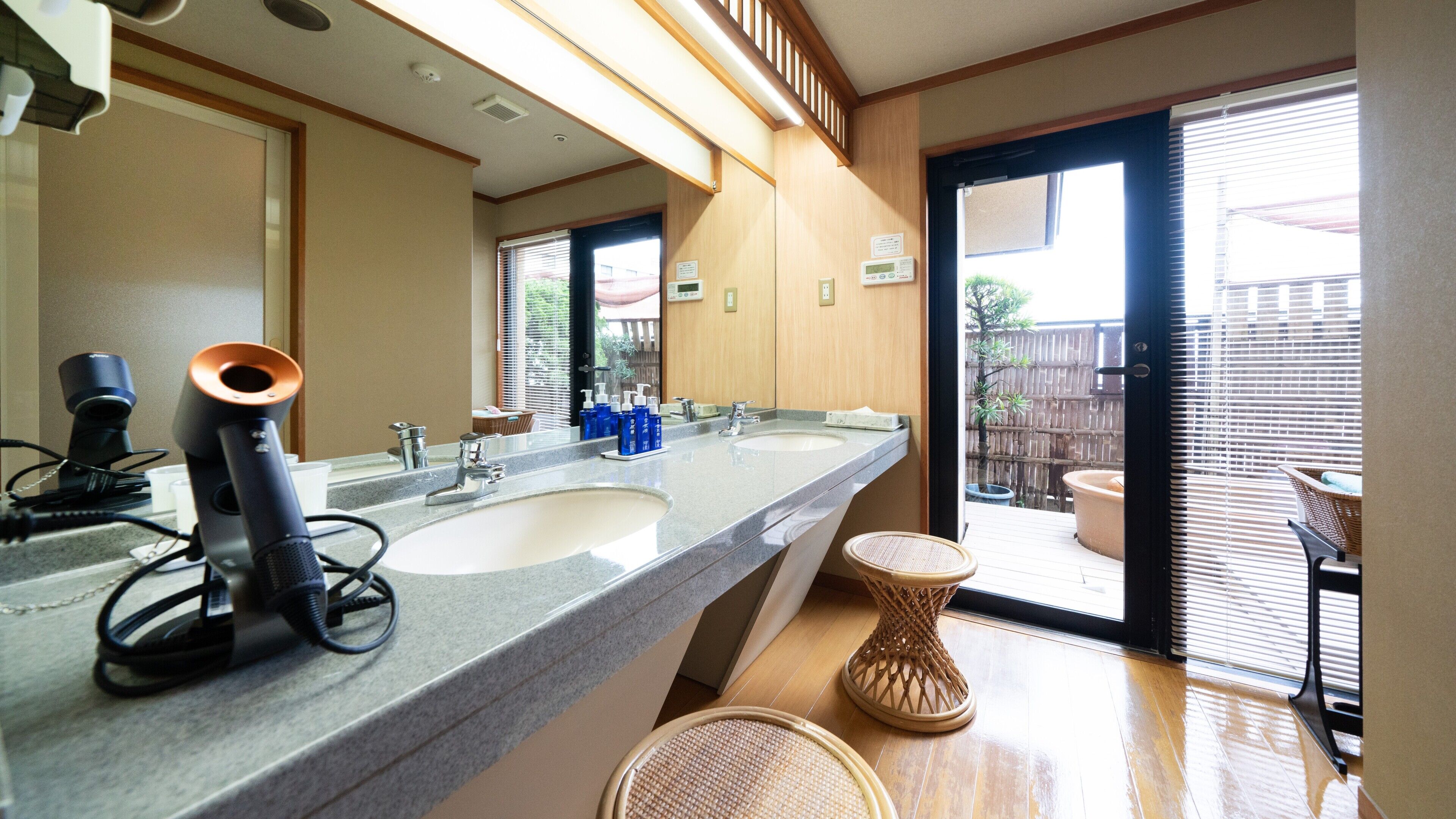 A bathroom with two sinks, a mirror, and a wicker stool.