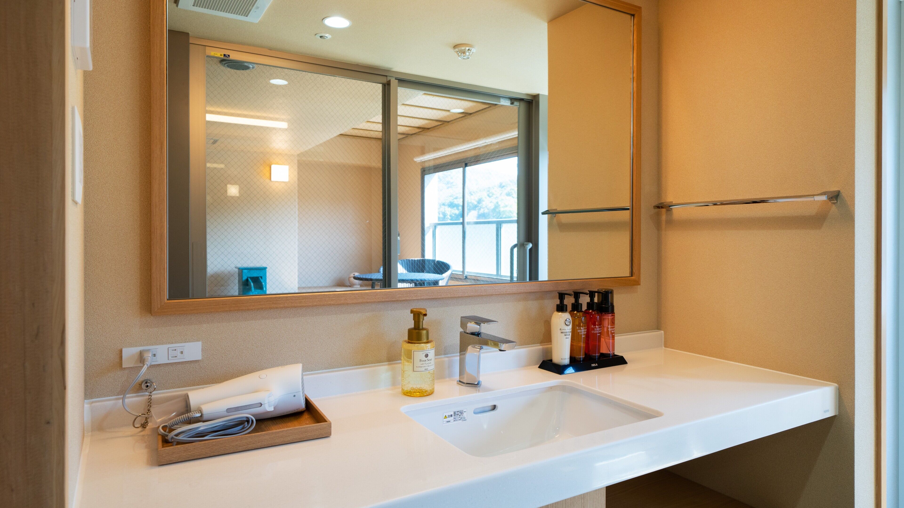 A bathroom with a large mirror, a sink, and toiletries.