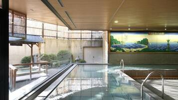 A swimming pool with a tiled floor, a metal handrail, and a mural on the wall.