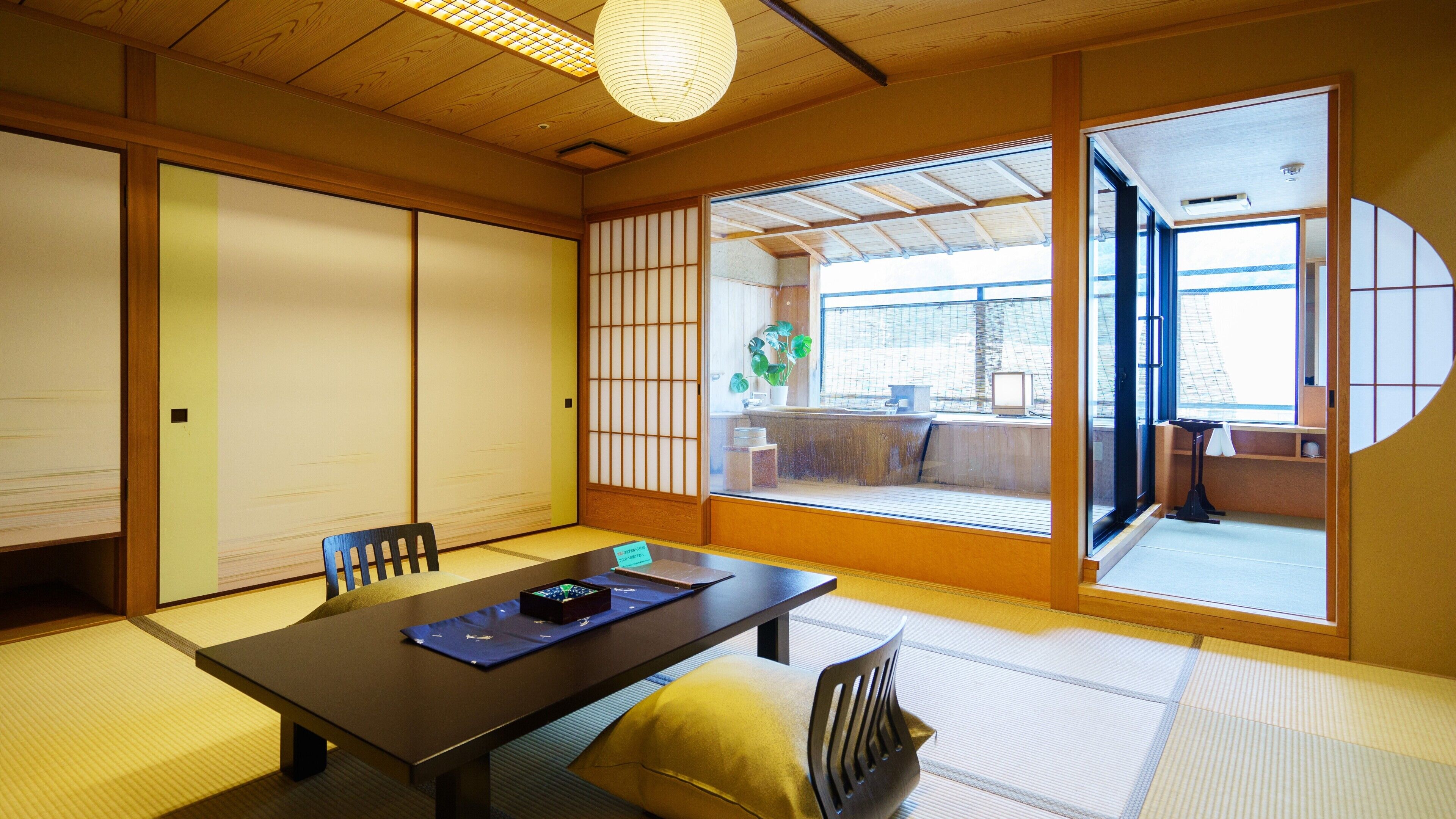 Una habitación tradicional japonesa con suelo de tatami, una mesa baja y puertas correderas.