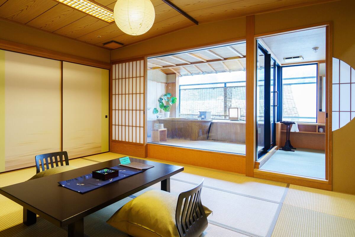 Una habitación tradicional japonesa con suelo de tatami, una mesa baja y puertas correderas.