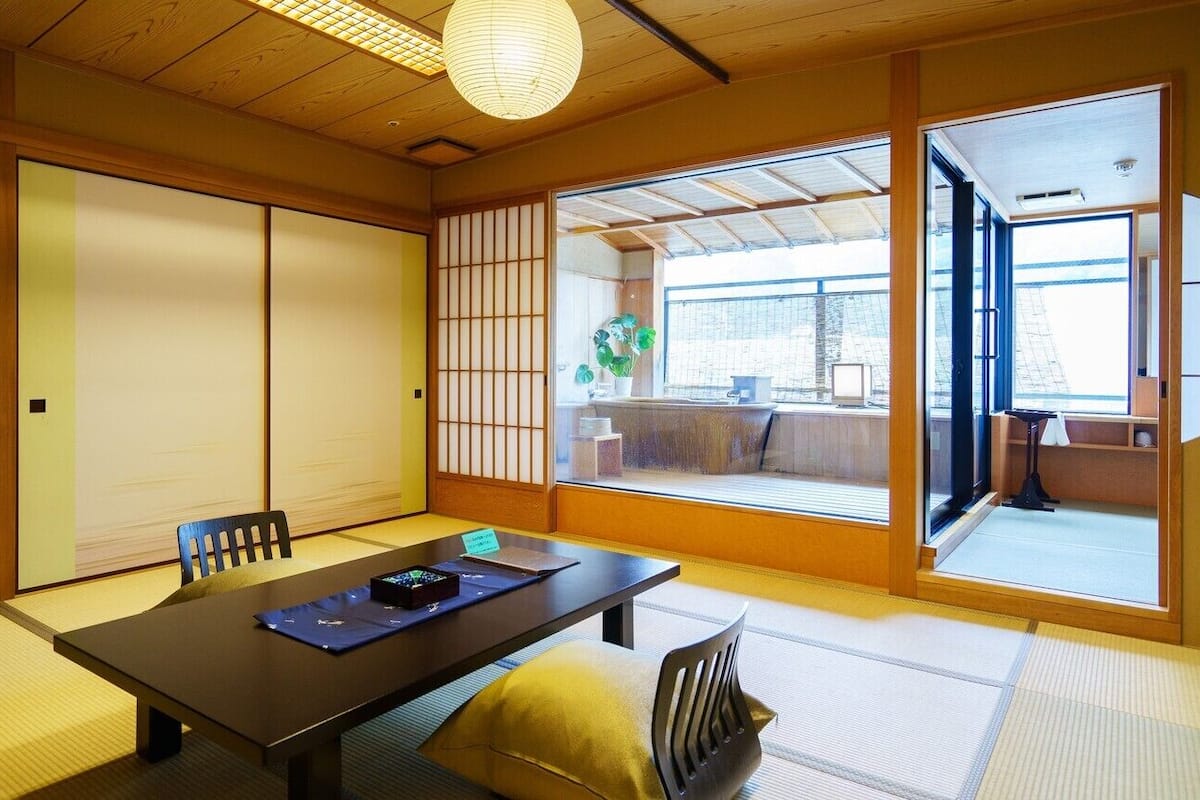 Una habitación tradicional japonesa con suelo de tatami, una mesa baja y puertas correderas.