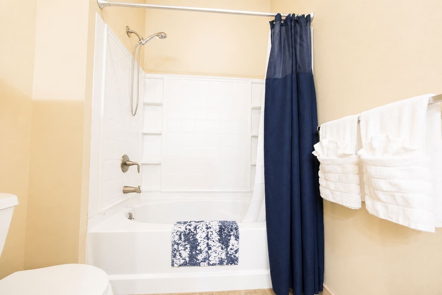 A bathroom with a bathtub, a shower, a toilet, and a towel rack with towels.