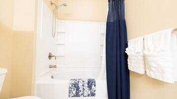 A bathroom with a bathtub, a shower, a toilet, and a towel rack with towels.