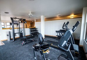 A gym with exercise equipment, a ceiling fan, and a window.