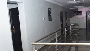A corridor with a metal railing, tiled floor, and a door at the end.