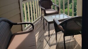 A covered porch with wicker furniture, a glass table, and a view of distant mountains. - View from the Top (Roseland)