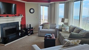A living room with a fireplace, a sofa, a coffee table, and a television. - View from the Top (Roseland)