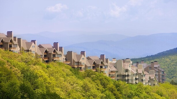 A row of multi-story buildings with balconies, set against a backdrop of mountains and greenery. - View from the Top (Roseland)