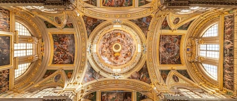 A grand, ornate ceiling with intricate frescoes and gold detailing.
