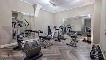 Un gimnasio con diversos equipos de ejercicio, entre ellos cintas de correr, una elíptica y pesas sueltas.