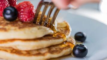 Pancakes con sciroppo e frutti di bosco su un piatto.