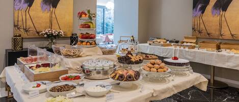 A buffet table with various food items and a vase of flowers.