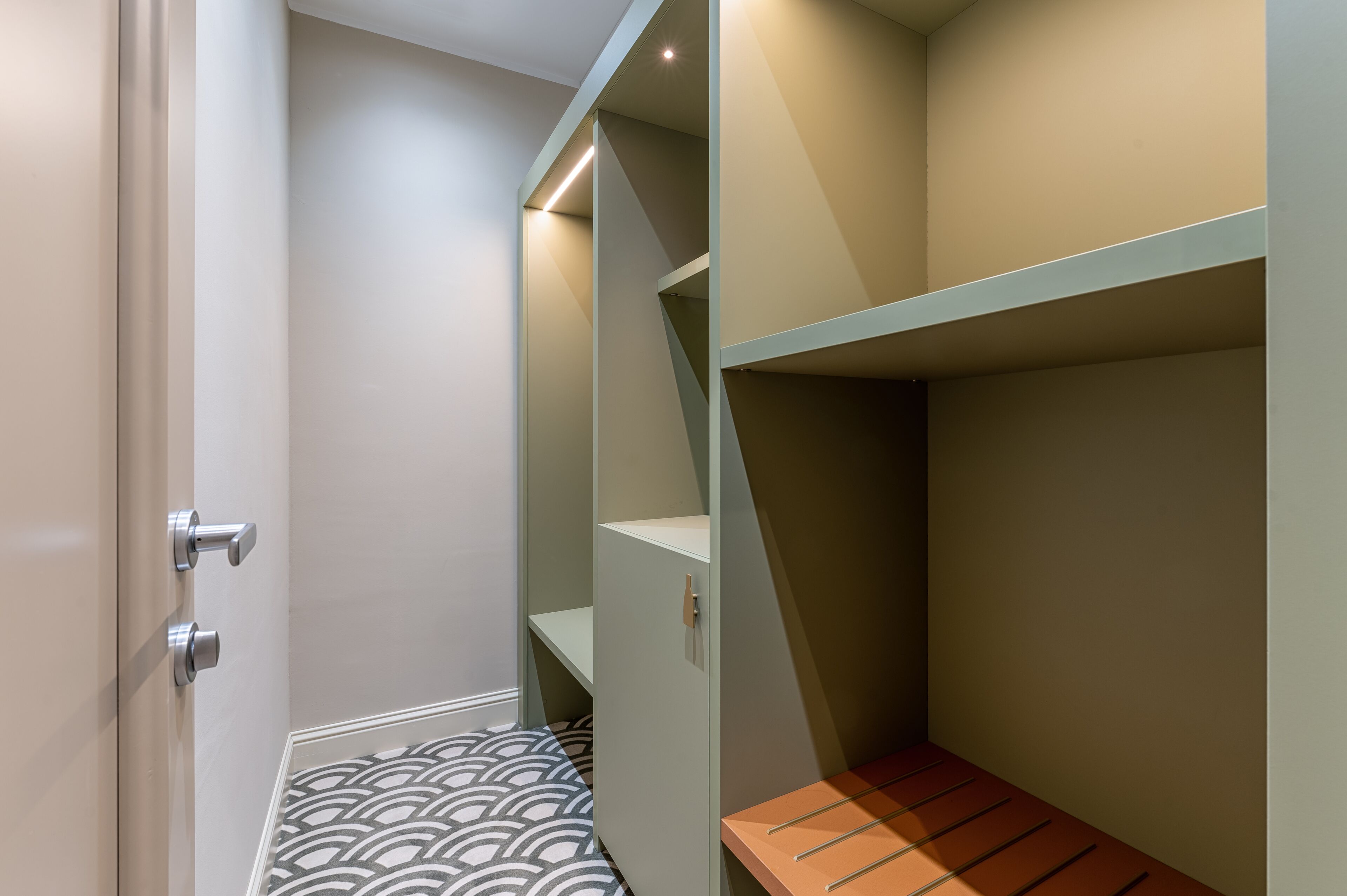 A compact room with a bunk bed, a small table, and a patterned floor.