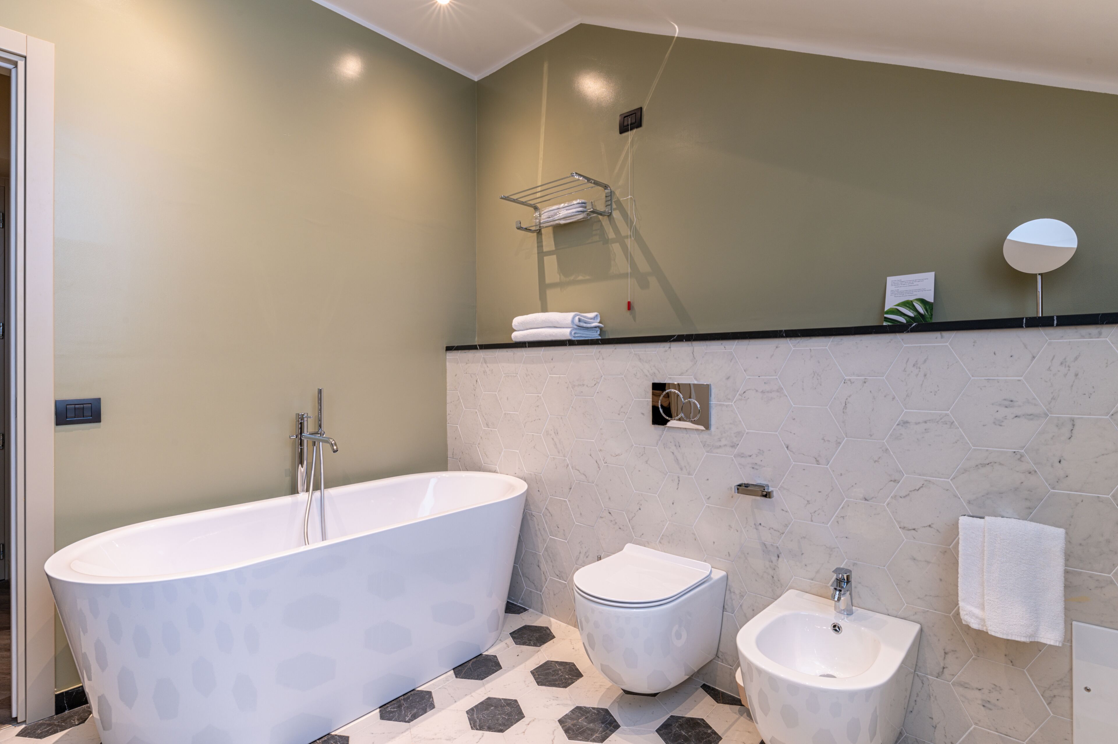 A modern bathroom with a freestanding bathtub, a toilet, and a bidet.