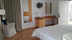 A hotel room with a bed, a desk, a chair, a television, and a mirror. - Nuevo Hotel Vista Alegre (Valdepenas)