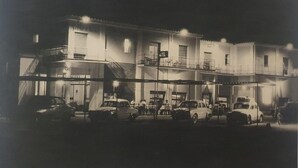 A hotel with multiple floors, balconies, and a sign indicating it is a hotel. There are several cars parked in front. - Nuevo Hotel Vista Alegre (Valdepenas)