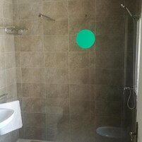 Ducha con puerta de cristal, lavamanos blanco y toallero.