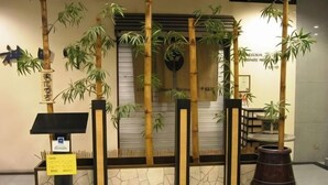 A reception area with bamboo plants, a stone wall, and a large wooden planter. - Hotel Royal Singapore (Singapore)