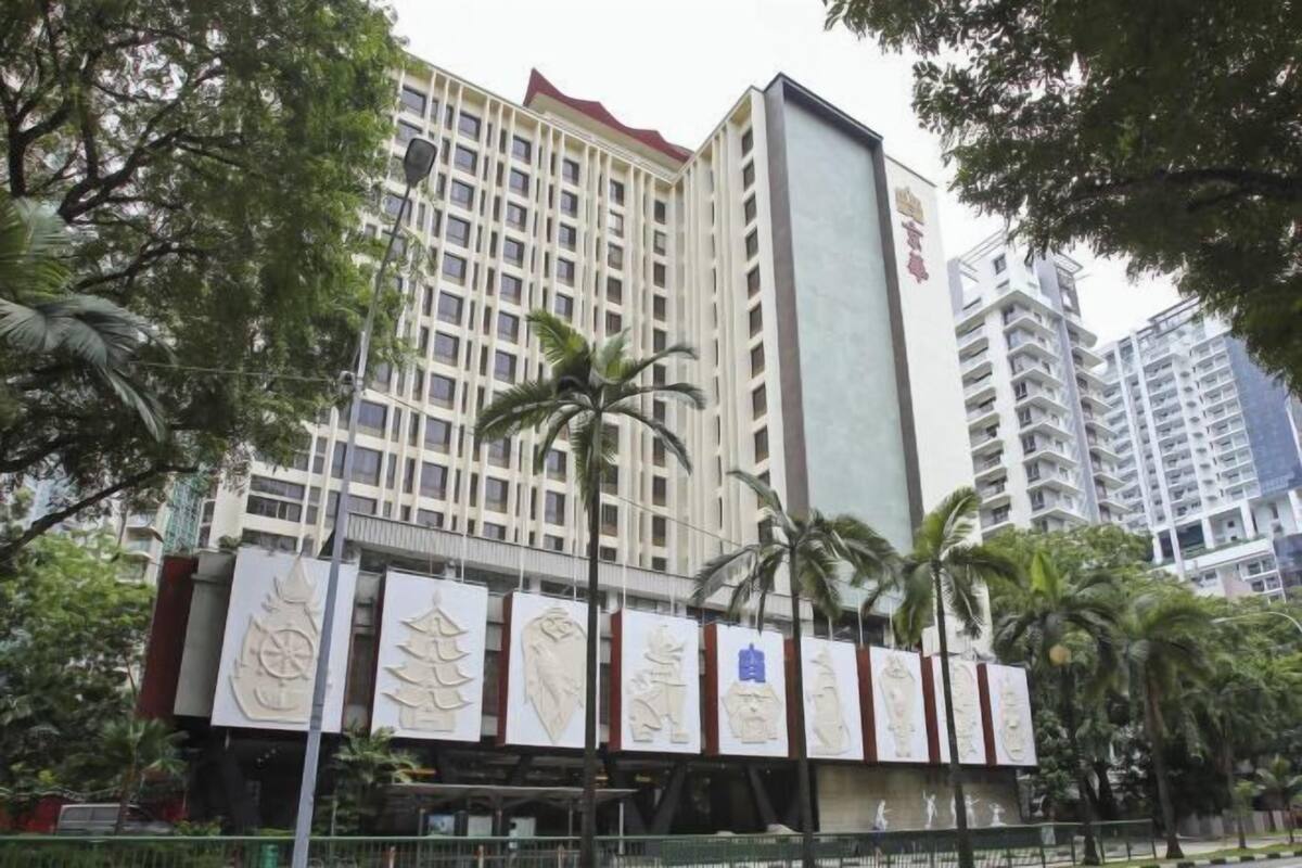 A multi-story building with a modern architectural design, featuring a prominent vertical structure and a series of banners with cultural motifs.