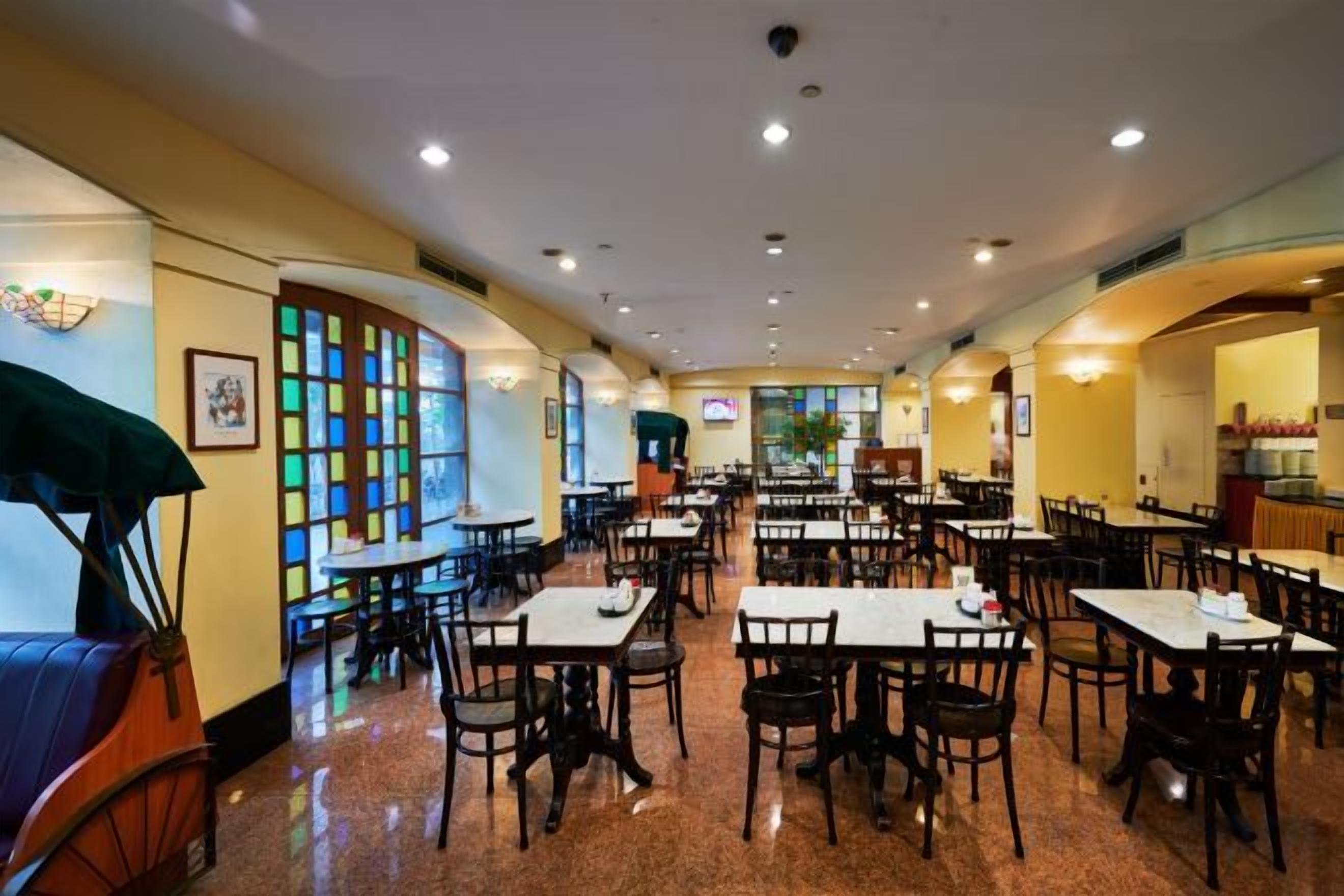 Un restaurante con varias mesas y sillas, una barra y vistas a la calle.