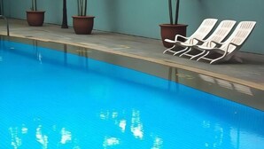 A swimming pool with lounge chairs and potted plants along the edge. - Hotel Royal Singapore (Singapore)