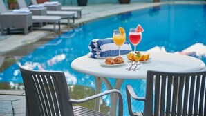 A poolside table with drinks, croissants, and a towel. - Hotel Royal Singapore (Singapore)