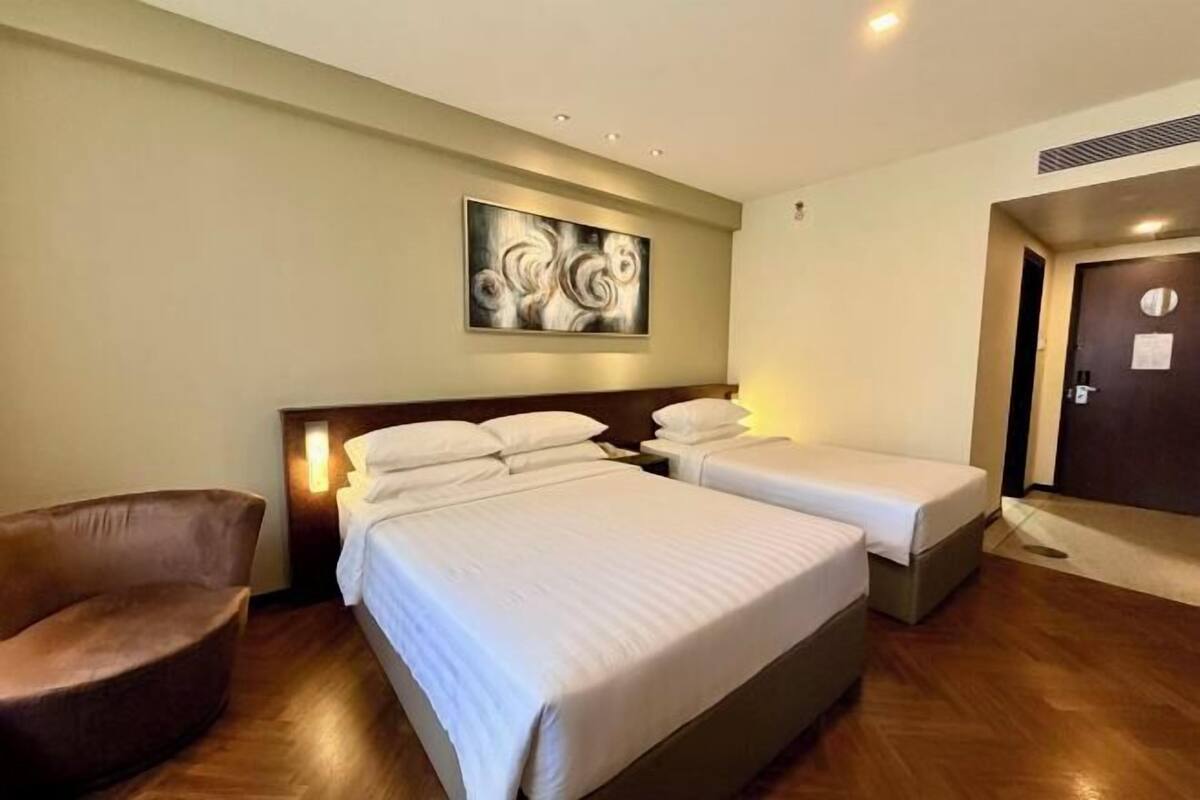 A hotel room with two beds, a chair, and a painting on the wall.