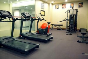 Une salle de sport équipée de tapis de course, d’un appareil elliptique et de machines de musculation.