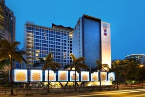 Un hotel con fachada moderna, varios pisos y señalización iluminada.