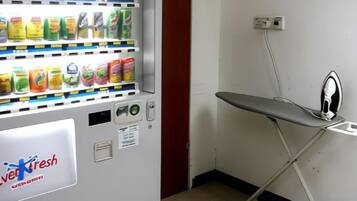 Máquina de vendas com área de produtos frescos e um ferro de passar sobre uma tábua.