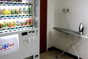 Máquina expendedora con una sección de productos frescos y una tabla de planchar con plancha.